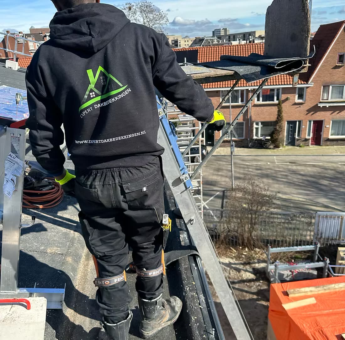 Dakdekker van Expert Dakbedekkingen hijst een rol dakbedekking omhoog met de ladderlift