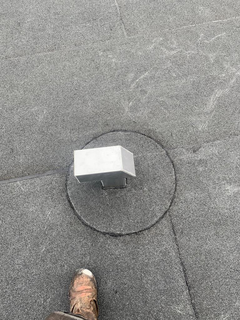 Dakdekker inspecteert een afvoer op een plat dak