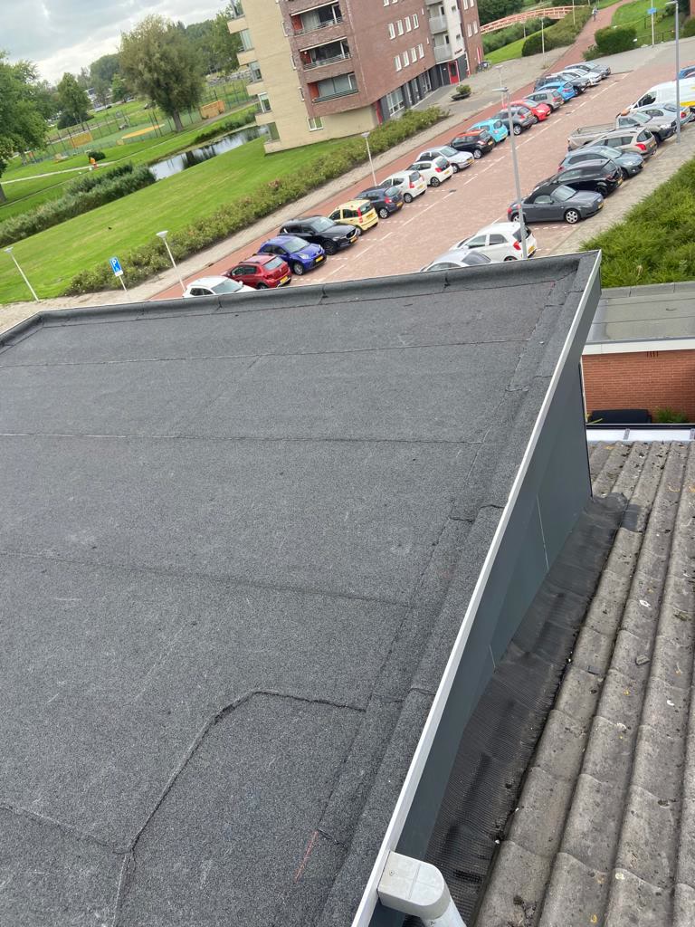 Plat dak van een appartementencomplex met uitzicht over de wijk
